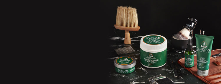 Collection of shaving products including a brush, soap, and cream on a dark surface.