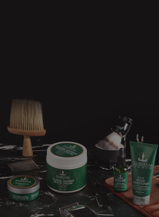 Collection of grooming products including a brush, jars, and bottles on a dark surface.