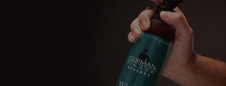 Hand holding a bottle of Clubman Pinaud Reserve with a dark background
